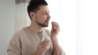 A man takes a pill with a glass of water